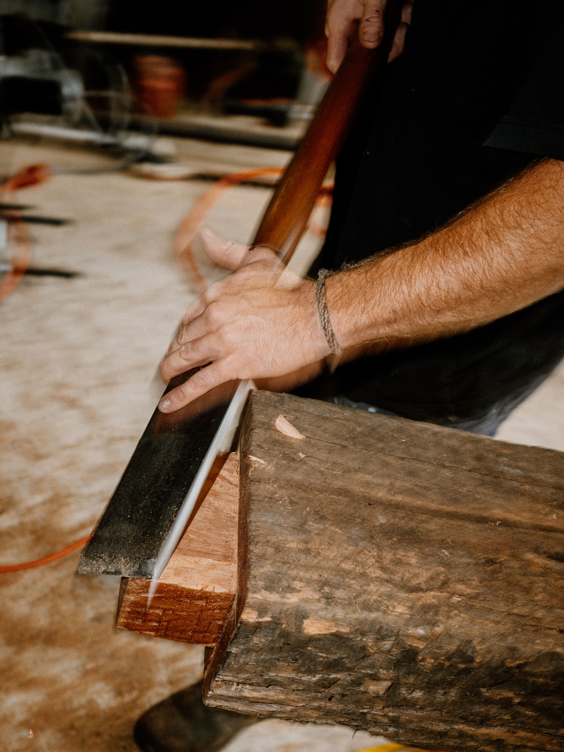 Hands guiding a hatchet along the chamfered corner of a beam