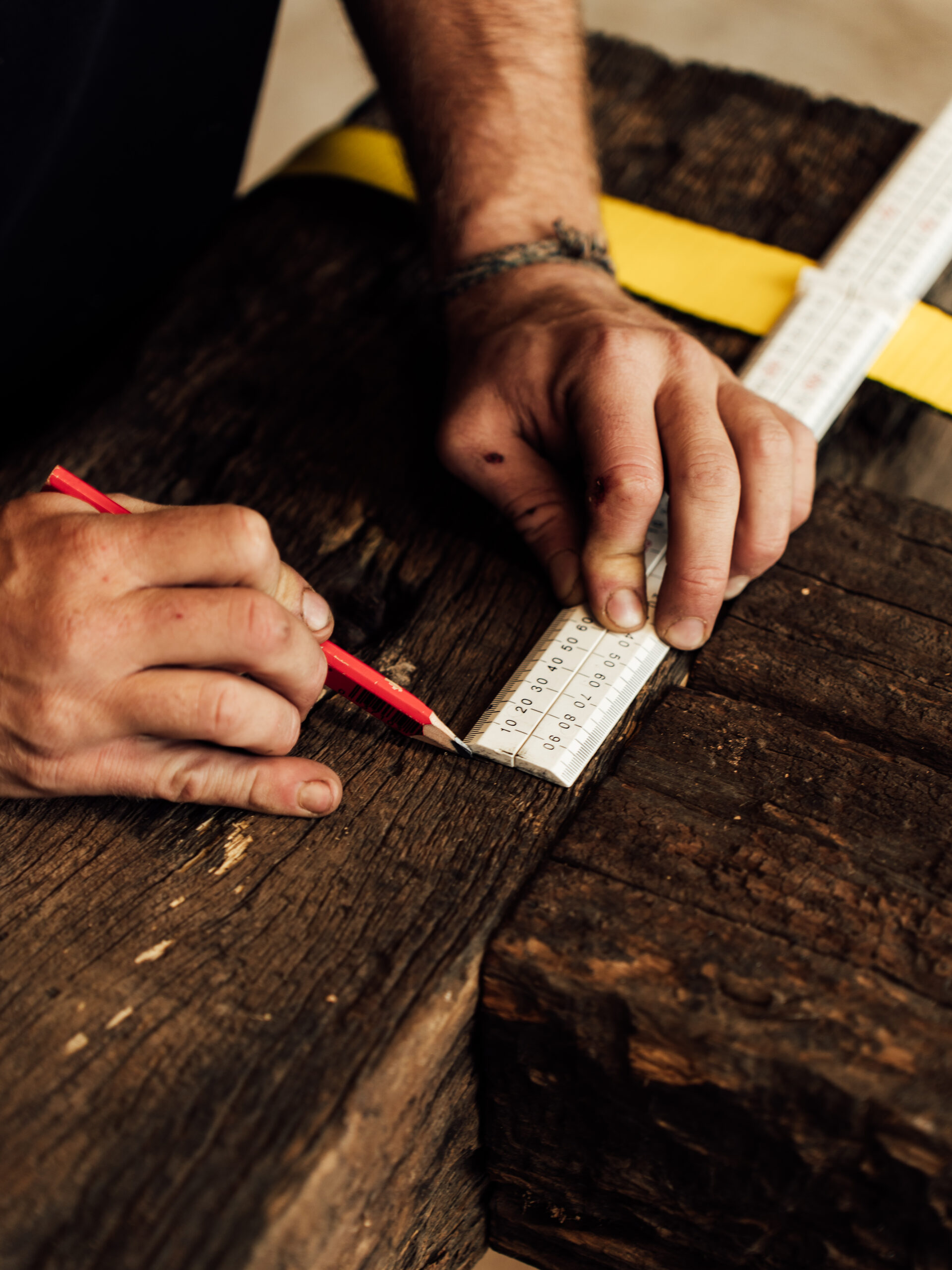 Marking a dark hardwood beam with a pencil and folding rule